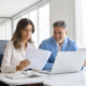 Side view of two professionals looking at financial document in modern office
